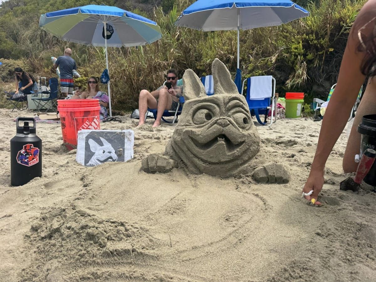 Sand sculpture of a smiling bulldog on the beach