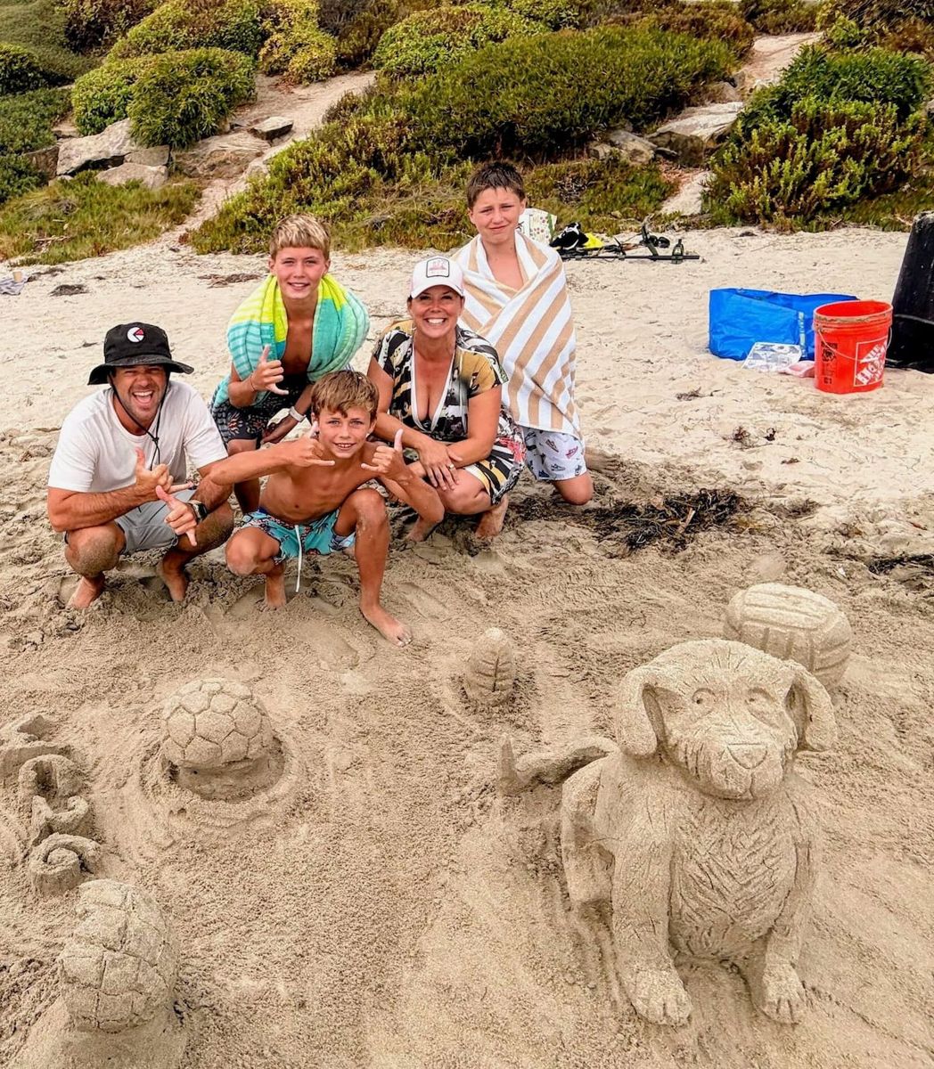 Family posing behind their sand dog sculpture