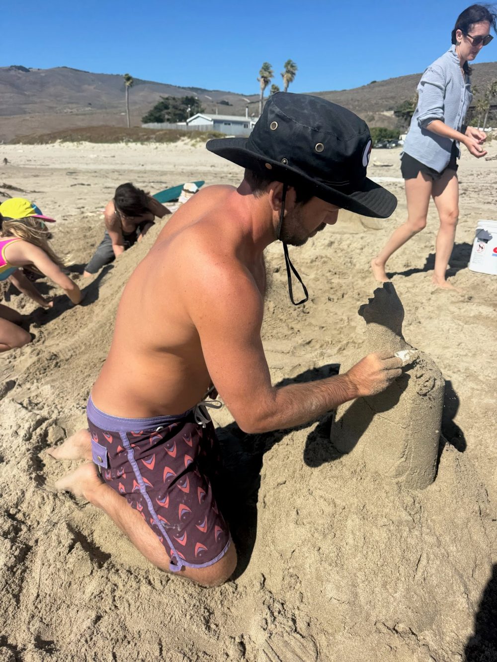 Mitchell carving a sand sculpture during a beach class